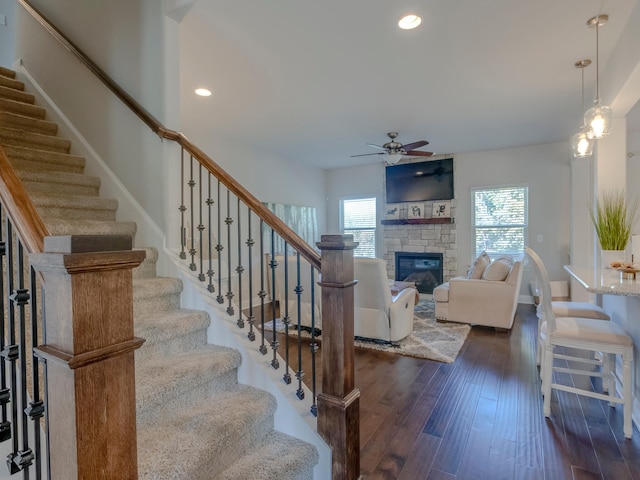 living room featuring ceiling fan, a fireplace, and dark hardwood / wood-style flooring