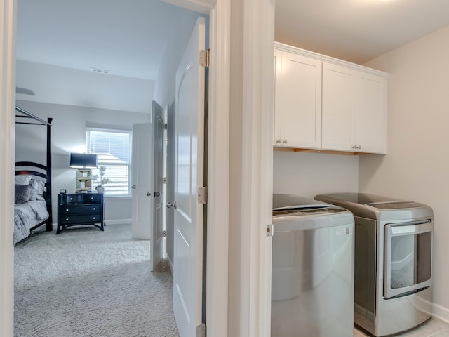 washroom with light colored carpet, washing machine and clothes dryer, and cabinets