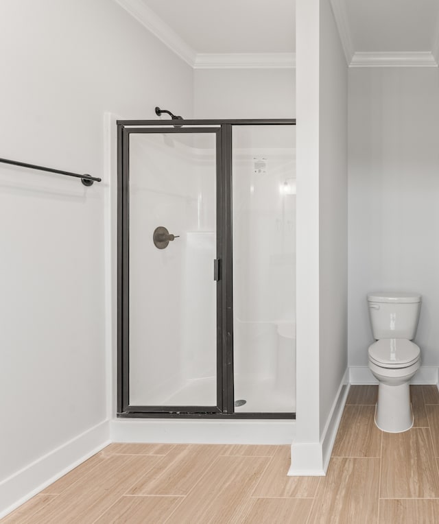 bathroom with crown molding, toilet, and a shower with door