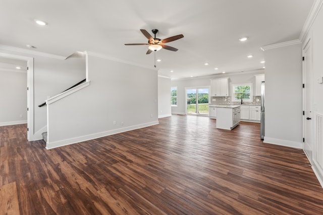 unfurnished living room with ornamental molding, ceiling fan, dark wood-type flooring, and sink