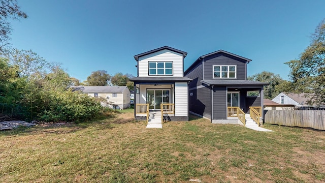 rear view of property featuring a yard and fence