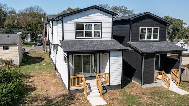 view of front of home with roof with shingles, a porch, and a front lawn