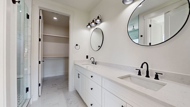 full bathroom featuring a sink, marble finish floor, a stall shower, and a spacious closet