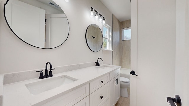 full bath featuring double vanity, toilet, visible vents, and a sink