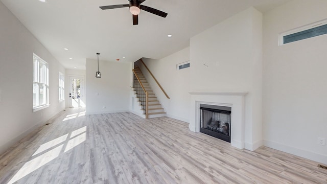 unfurnished living room with stairs, recessed lighting, a fireplace, and light wood-style floors