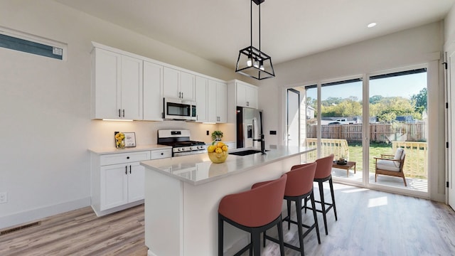 kitchen with a sink, stainless steel appliances, light wood-style floors, a breakfast bar area, and light countertops