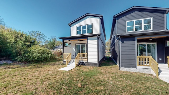 back of property featuring ceiling fan and a yard