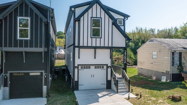 tudor home featuring a garage, a front yard, board and batten siding, and driveway