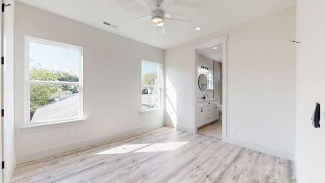 bedroom with ensuite bathroom, baseboards, visible vents, and light wood finished floors