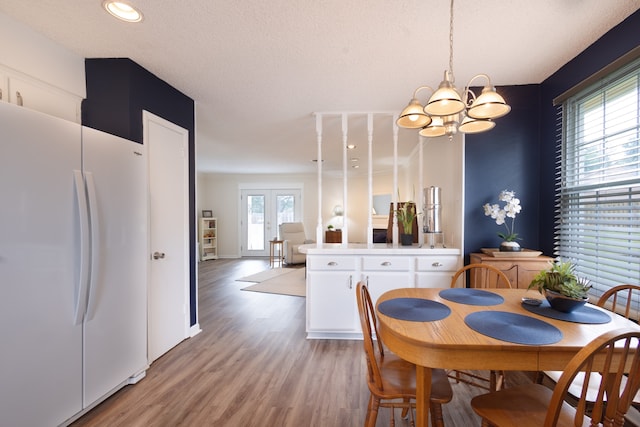 dining space featuring plenty of natural light, french doors, light hardwood / wood-style flooring, and a textured ceiling