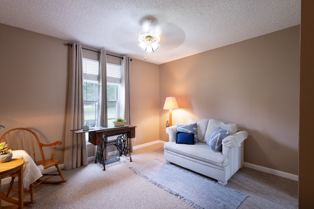 sitting room with light carpet, ceiling fan, and a textured ceiling