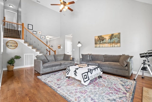 living room with a high ceiling, hardwood / wood-style flooring, and ceiling fan