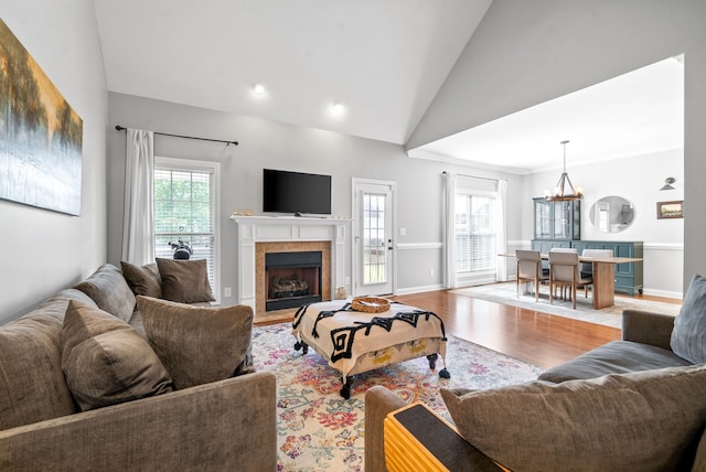 living room with high vaulted ceiling, a chandelier, and light hardwood / wood-style flooring