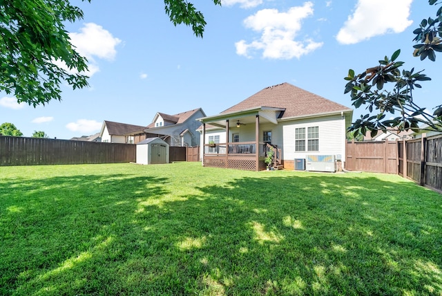 back of property with a yard, a wooden deck, cooling unit, and a storage shed