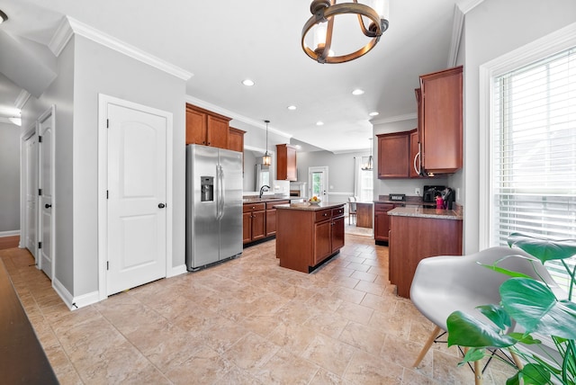 kitchen with pendant lighting, stainless steel fridge, a kitchen island, light stone countertops, and crown molding