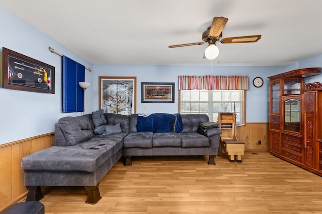 living room with ceiling fan, wood walls, and light hardwood / wood-style flooring