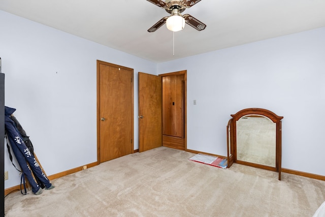 unfurnished bedroom featuring ceiling fan, light colored carpet, and two closets