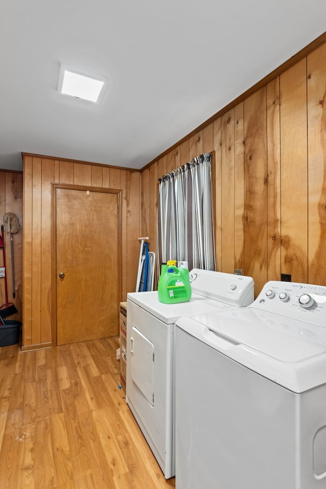 washroom with wood walls, washing machine and dryer, and light hardwood / wood-style flooring