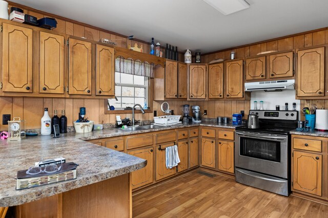 kitchen with kitchen peninsula, light wood-type flooring, stainless steel electric range oven, and sink