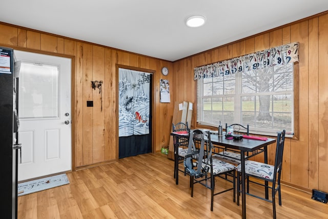 dining space featuring light hardwood / wood-style flooring and wood walls