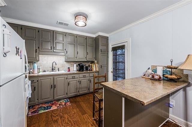 kitchen with sink, kitchen peninsula, white fridge, a kitchen bar, and dark hardwood / wood-style flooring