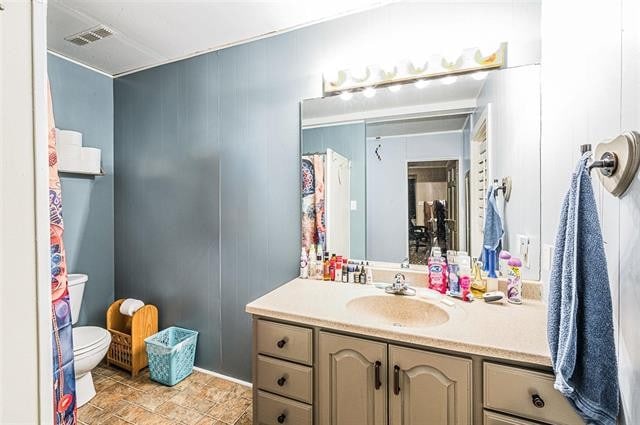 bathroom with vanity, wooden walls, and toilet