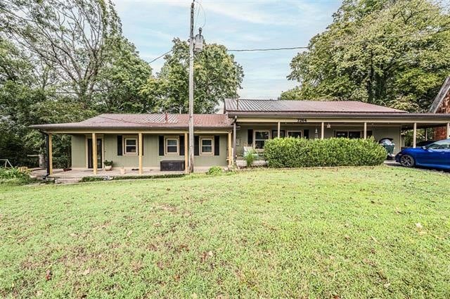 view of front of home with a front yard, a porch, and a carport