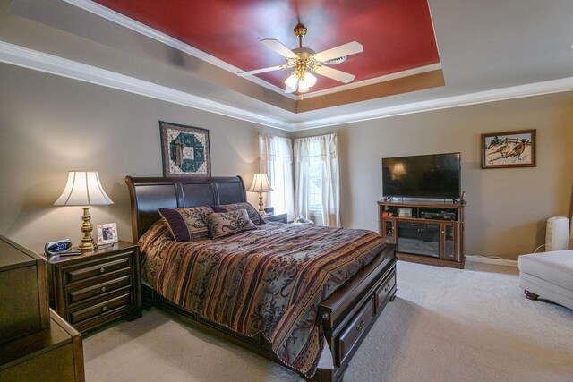 carpeted bedroom featuring ornamental molding, ceiling fan, and a tray ceiling