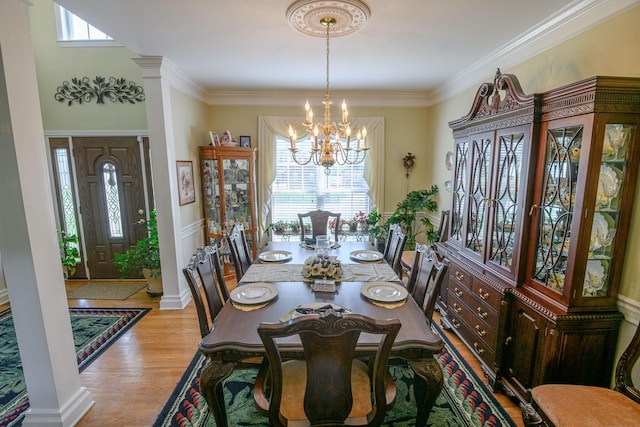 dining space with an inviting chandelier, ornamental molding, light hardwood / wood-style floors, and decorative columns