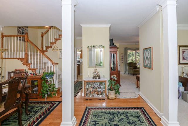 hall featuring hardwood / wood-style flooring, ornamental molding, and decorative columns