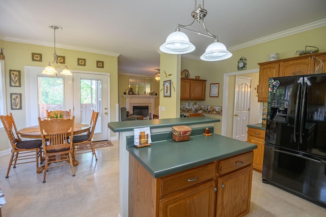 kitchen featuring pendant lighting, ornamental molding, black fridge with ice dispenser, and a kitchen island