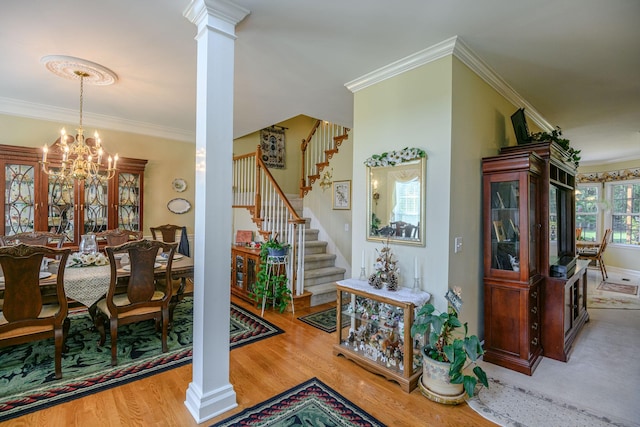 dining room featuring decorative columns, crown molding, an inviting chandelier, and light hardwood / wood-style flooring