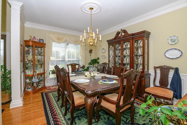 dining room featuring decorative columns, ornamental molding, an inviting chandelier, and light wood-type flooring