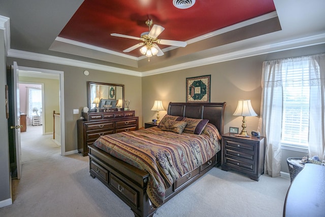 bedroom with light carpet, a tray ceiling, and crown molding