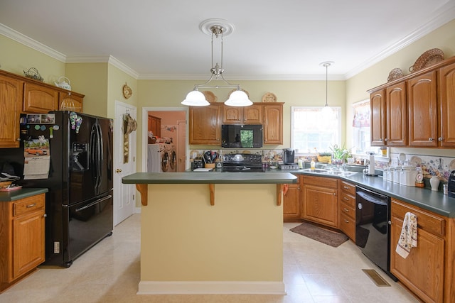 kitchen featuring washing machine and clothes dryer, a center island, hanging light fixtures, and black appliances