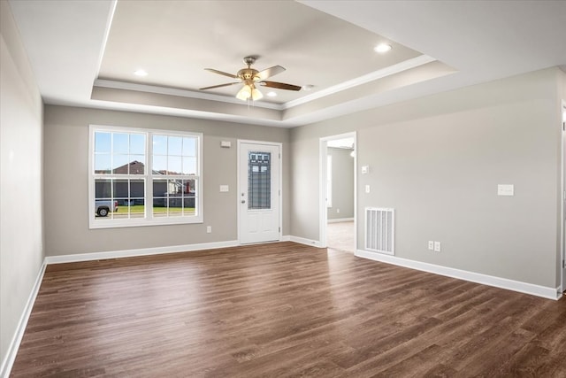 interior space with dark hardwood / wood-style floors, ceiling fan, a raised ceiling, and ornamental molding