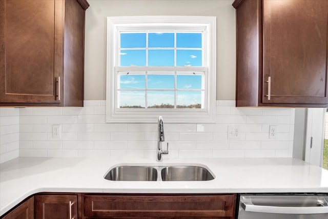 kitchen featuring stainless steel dishwasher, dark brown cabinetry, sink, and tasteful backsplash