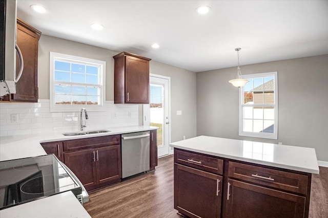 kitchen featuring sink, dark wood-type flooring, backsplash, decorative light fixtures, and appliances with stainless steel finishes