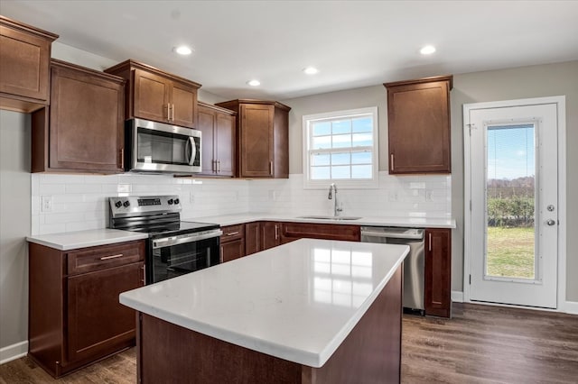 kitchen featuring sink, dark hardwood / wood-style floors, tasteful backsplash, a kitchen island, and stainless steel appliances