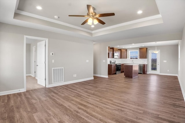 unfurnished living room featuring dark hardwood / wood-style floors, a raised ceiling, ceiling fan, and crown molding