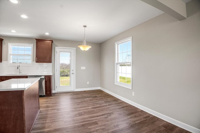 kitchen featuring backsplash, dark wood-type flooring, sink, stainless steel dishwasher, and decorative light fixtures