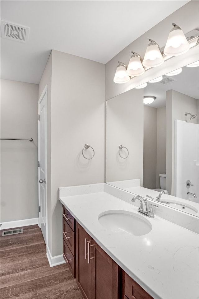 full bathroom featuring washtub / shower combination, wood-type flooring, vanity, and toilet