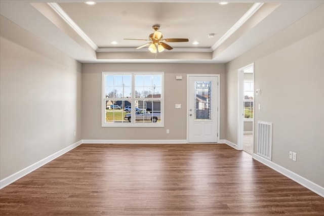 interior space with ceiling fan, dark hardwood / wood-style flooring, crown molding, and a tray ceiling