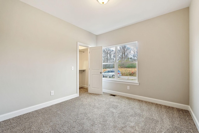 unfurnished bedroom with carpet, a spacious closet, and a closet