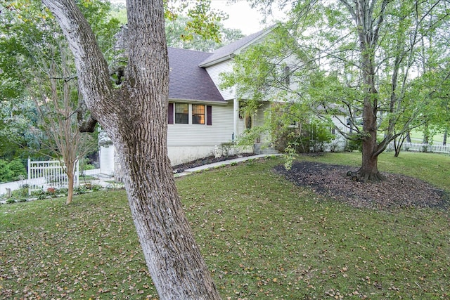 view of home's exterior featuring fence, a lawn, and roof with shingles