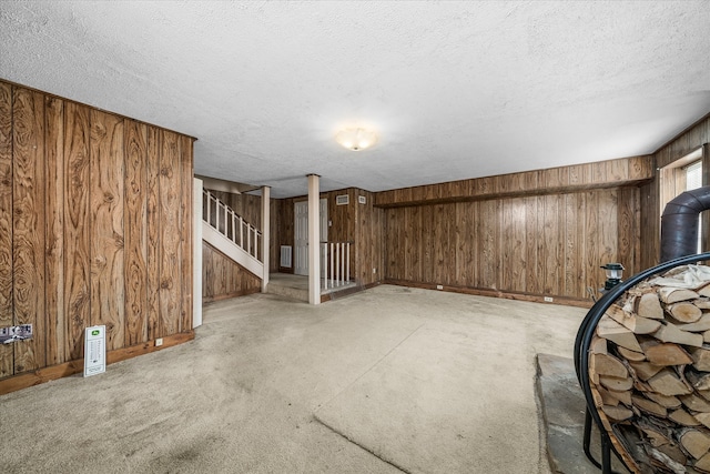 basement with wood walls, a textured ceiling, and light carpet