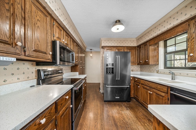 kitchen with a textured ceiling, appliances with stainless steel finishes, dark hardwood / wood-style floors, and sink