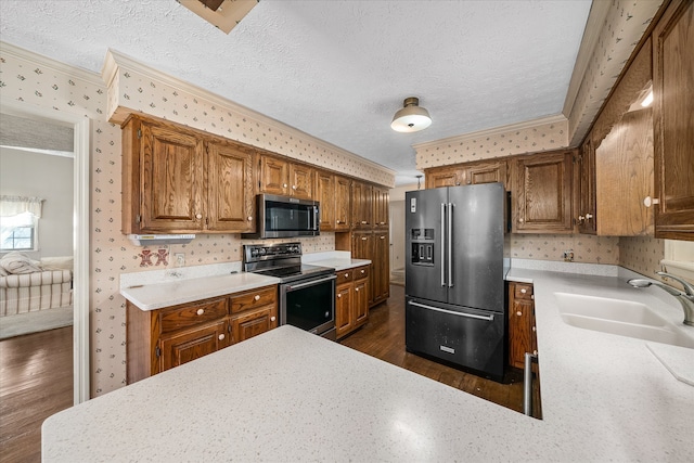 kitchen with dark wood-type flooring, appliances with stainless steel finishes, sink, and ornamental molding