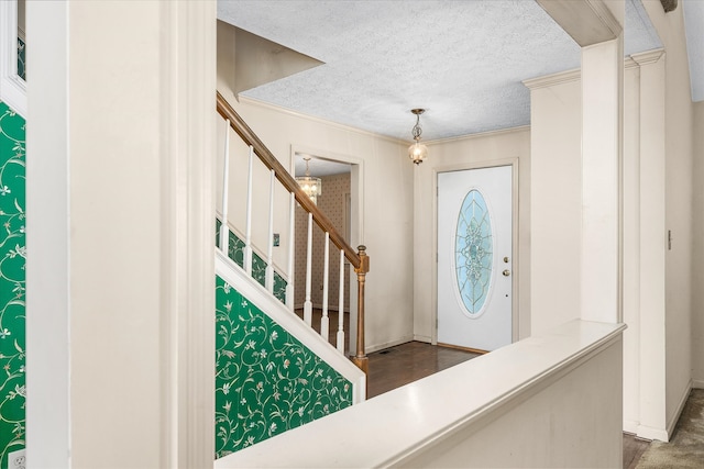 foyer featuring dark wood-type flooring, a textured ceiling, and ornamental molding