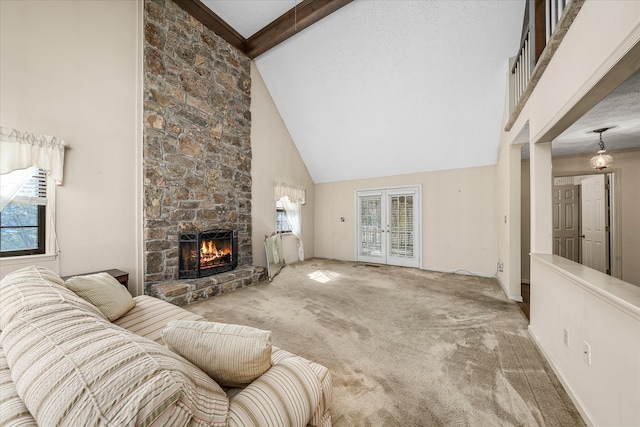 carpeted living room with a stone fireplace, high vaulted ceiling, beamed ceiling, and french doors